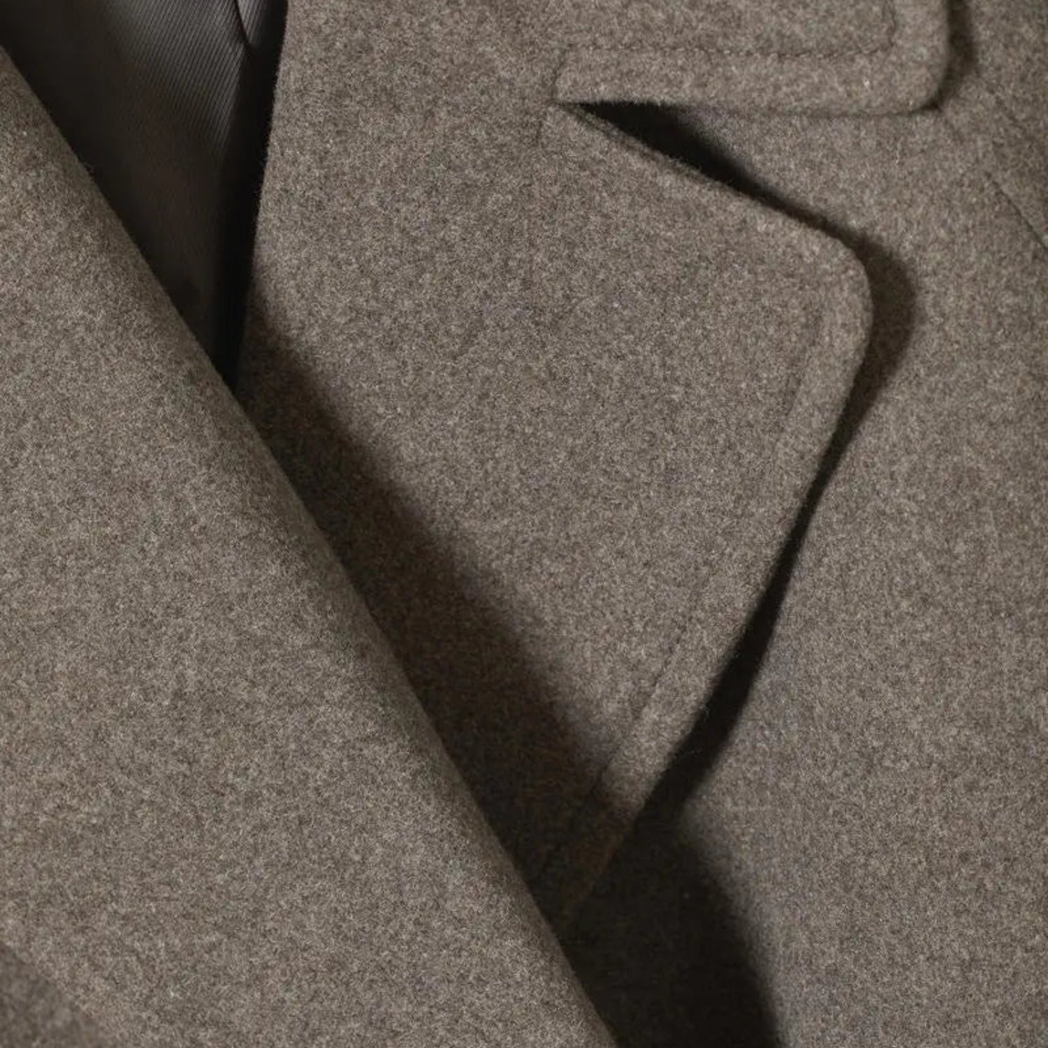 Detailaufnahme des taupefarbenen Wollstoffs mit Reverskragen – Langer Wollmantel im Oversize-Stil für Damen