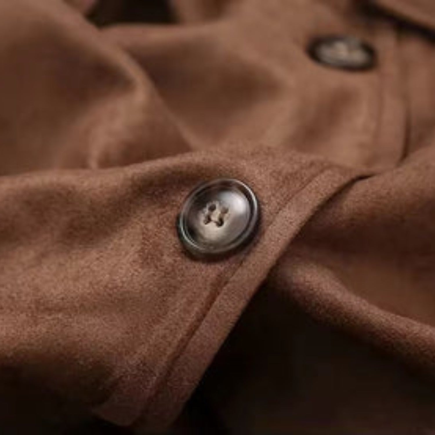 Detailaufnahme des braunen Premium Wildleder-Trenchcoats für Damen: hochwertiger Knopf an der Manschette auf weichem Wildleder.