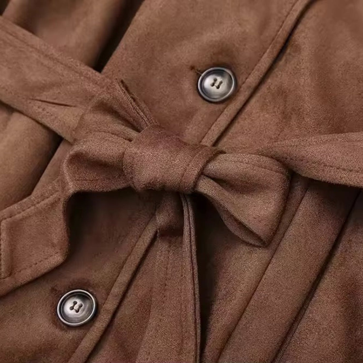 Detailaufnahme des braunen Premium Wildleder-Trenchcoats für Damen: Taillengürtel zum Binden mit Knopfleiste auf weichem Wildleder.