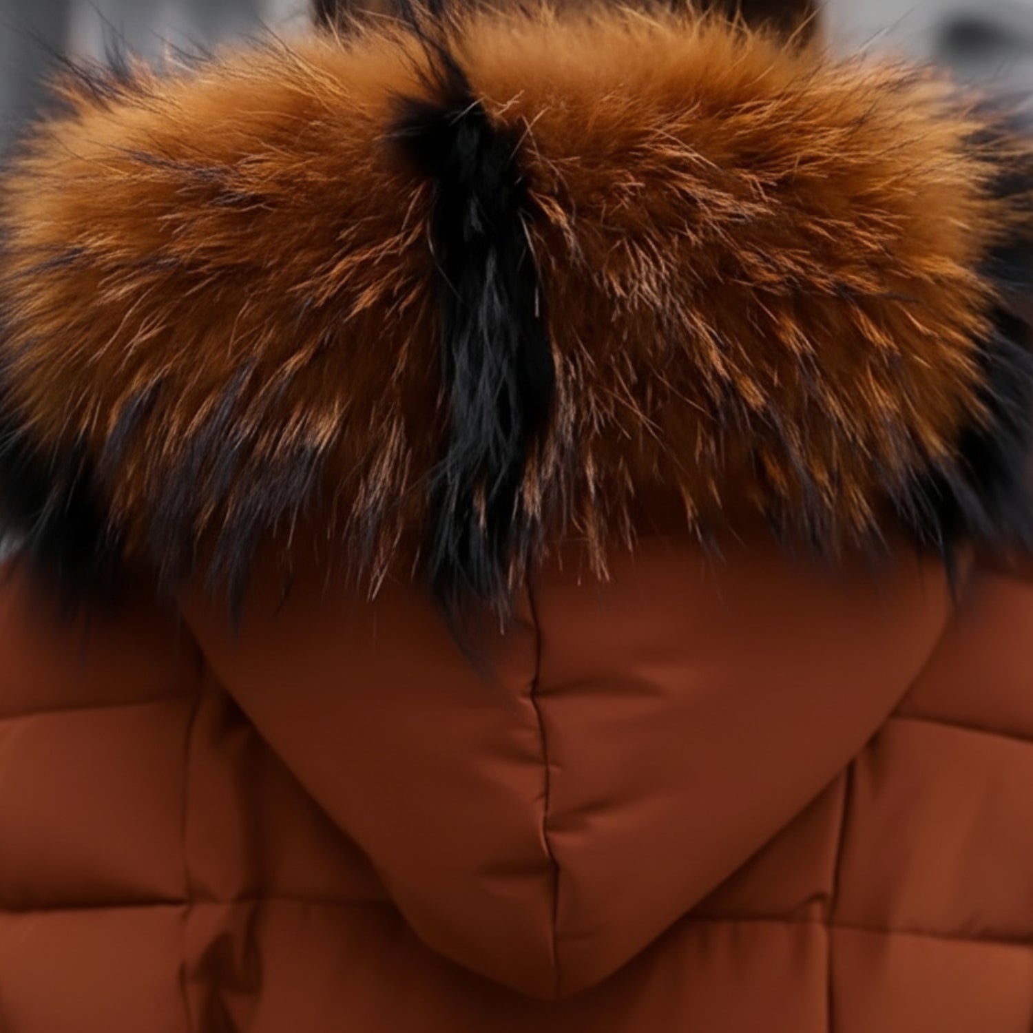 Detailansicht des warmen, bauschigen Wintermantels für Damen in Rostbraun – Nahaufnahme der Kapuze mit vollem Kunstfellbesatz